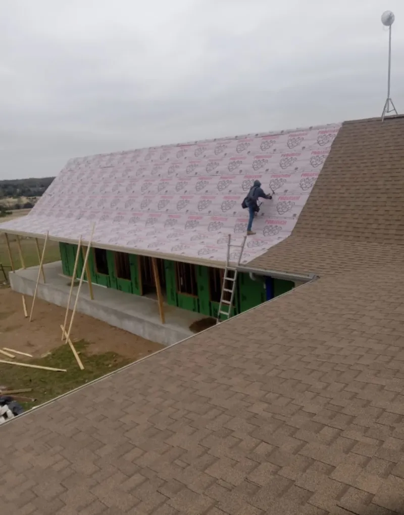Worker preparing underlayment for a metal roof installation in Columbus